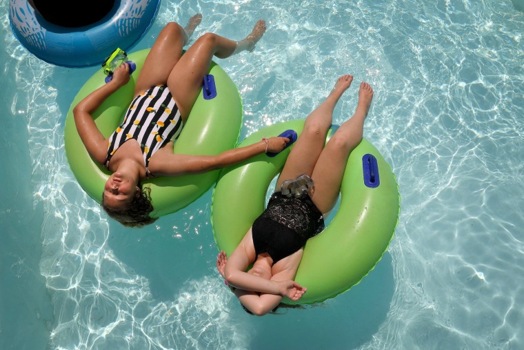 Image: Mya Jones, left, 12, and her cousin Alexis Carlen, 13, keep cool on a tubes floating around the Endless River at Raging Rivers Waterpark in Grafton
