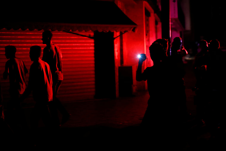 Image: People walk on the street during a blackout in Caracas