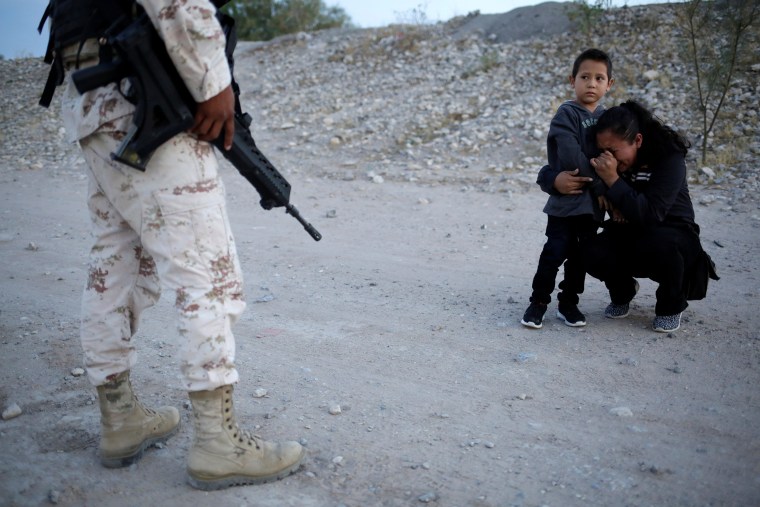 Image: Guatemalan migrant Lety Perez embraces her son Anthony while praying to ask a member of the Mexican National Guard to let them cross into the United States, as seen from Ciudad Juarez