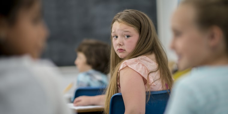 Young girl looks worried and hurt in classroom.