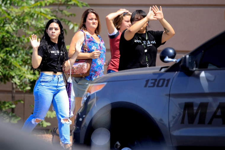 Image: Shoppers exit with their hands up after a mass shooting at a Walmart in El Paso