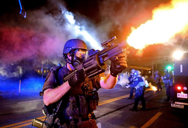 Image: A member of the St. Louis County Police tactical team fires tear gas into a crowd of people in response to a series of gunshots fired at police during demonstrations in Ferguson, Missouri