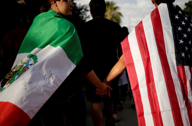 Image: People wearing a Mexican and American flags hold hands in a rally against hate the day after a mass shooting in El Paso, Texas, on Aug. 4, 2019.