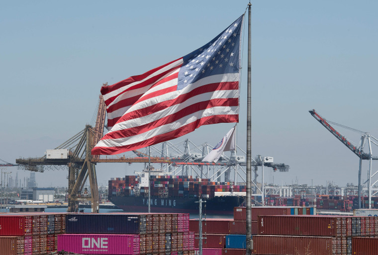 Image: The U.S. flag flies over a container ship unloading it's cargo from Asia, at the Port of Long Beach, California