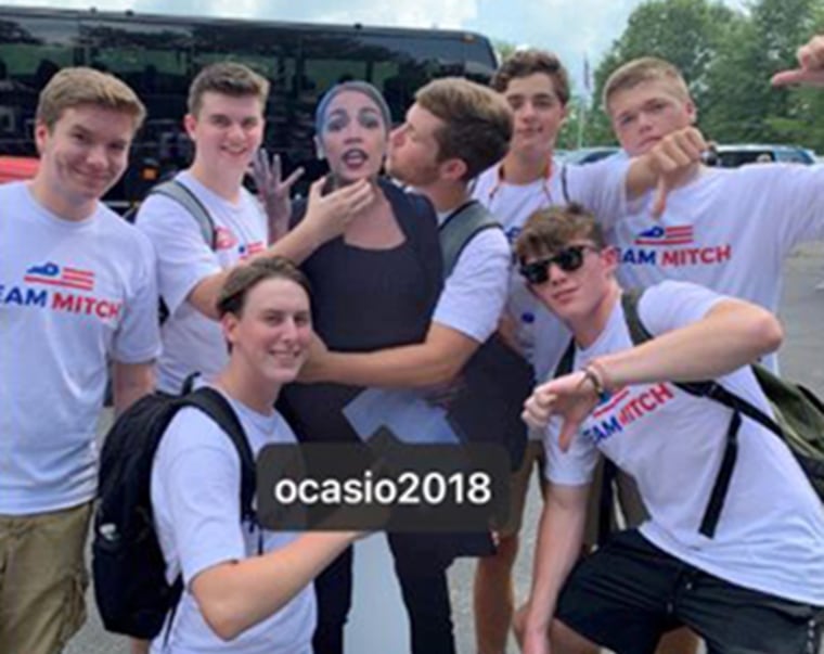 Image: Young men grope and choke a cardboard cutout of Rep. Alexandria Ocasio-Cortez while wearing "Team Mitch" shirts.