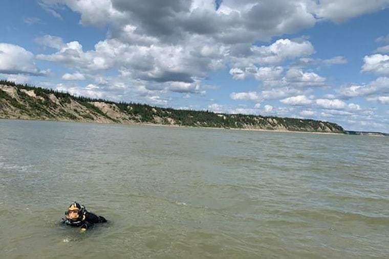 Image: A Royal Canadian Mounted Police (RCMP) diver, part of the law enforcement team looking for fugitive murder suspects Kam McLeod and Bryer Schmegelsky, searches the Nelson River after a damaged aluminum boat was found nearby in Sundance, Manitoba, Ca