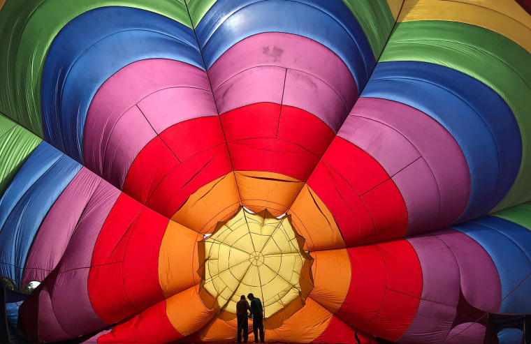 Image: Two crew members inspect a partially inflated balloon at the annual Bristol hot air balloon festival in Bristol, Britain