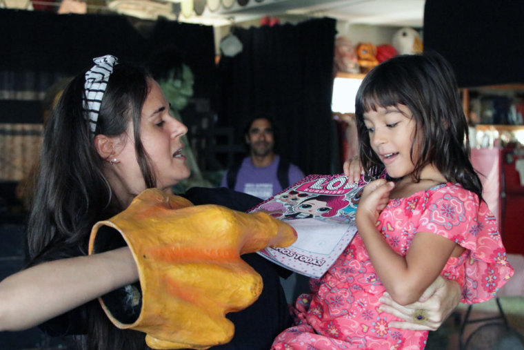 Yari Helfeld, co-director of Puerto Rican theater company Y No Habia Luz, reads a children's book to a girl in San Juan, Puerto Rico.