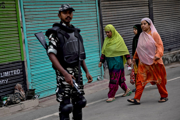 Image: Kashmiri women walk past security personnel as the Indian government imposes restrictions on the Kashmir region on Aug. 11, 2019.