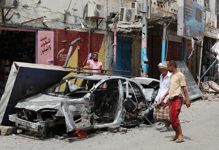 Image: Residents check cars that were burned during clashes in Aden 