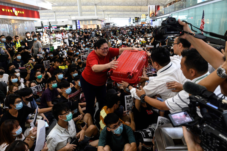 Image: A tourist gives her luggage to security guards as she tries to enter the departures gate during another demonstration by pro-democracy protesters at Hong Kong's international airport