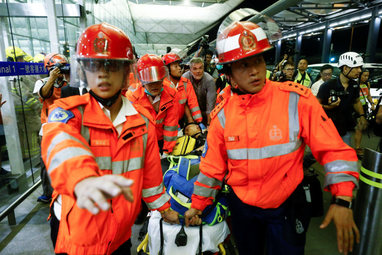 Image: Medics remove an injured man who anti-government protesters said was an undercover policeman at the airport in Hong Kong