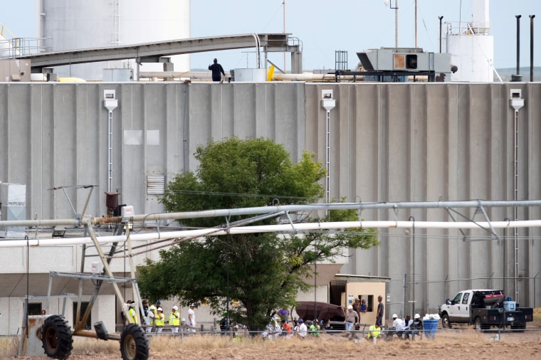 Image: Workers sit outside the Tyson Fresh Meats processing plant after a fire damaged the facility in Holcomb, Kansas, on Aug. 12, 2019.