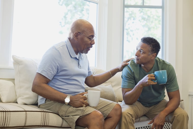 Image; Senior father and son talking while having coffee on sofa