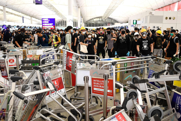 Image: Pro-democracy protesters block the entrance to the airport terminals after a scuffle with police at Hong Kong's international airport