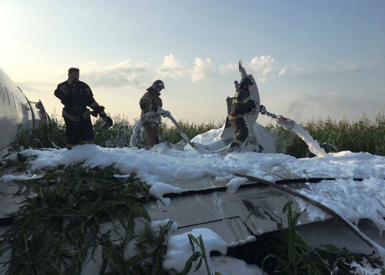 Image: Firefighters spray foam on a passenger plane following an emergency landing near Moscow