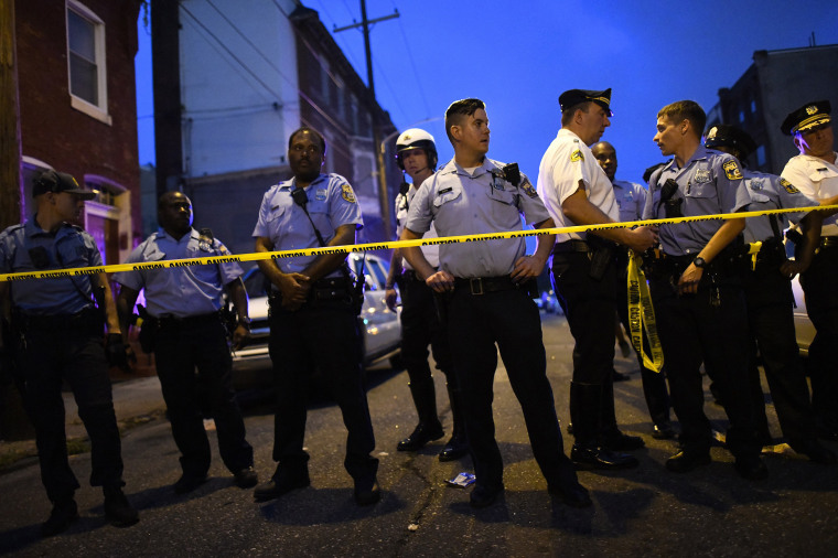 Police officers monitor activity near a residence while responding to a shooting in Philadelphia on Aug.14, 2019.