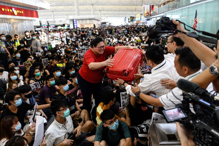 A tourist gives her luggage to security guards as she tries to enter the departures gate during a demonstration by pro-democracy protesters at Hong Kong's international airport on Aug. 13, 2019.