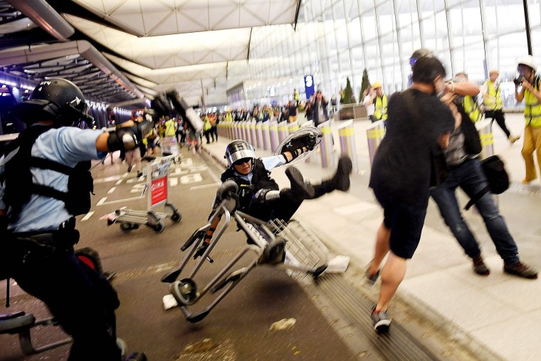 A policeman falls backwards during demonstrations at Hong Kong's International Airport on Aug. 13, 2019.