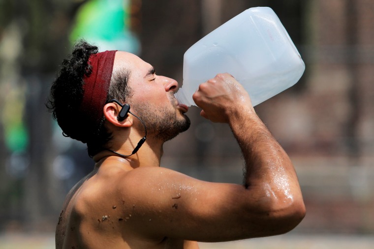 Image: Justin Dagostino, 27, from Manhattan, drinks water while training as a heatwave continued to affect the region in Manhattan, New York City