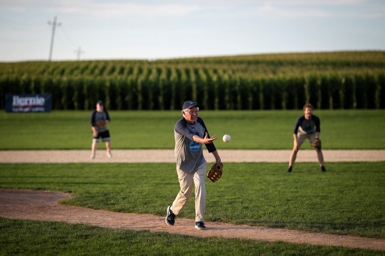Image: 2020 Democratic U.S. presidential candidate and U.S. Senator Bernie Sanders pitches during a baseball game between his staff, \"The Revolutionaries,\" and the Leaders Believers Achievers Foundation at the \"Field of Dreams\" movie site in Dyersville