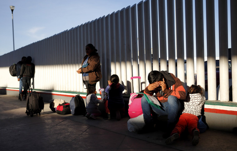Image: A migrant sits with his children to apply for asylum to the United States at the border with Mexico in Tijuana on Jan. 25, 2019.