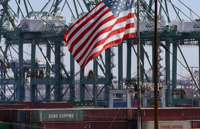 Image: The U.S. flag flies over Chinese shipping containers that were unloaded at the Port of Long Beach, in Los Angeles County.