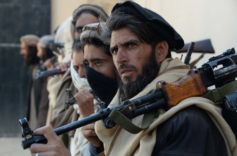 Image: Afghan alleged former Taliban fighters carry their weapons before handing them over as part of a government peace and reconciliation process.