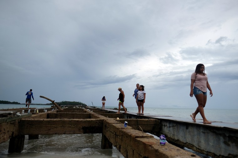 Image: People walk over a deck as Tropical Storm Dorian approaches in Humacao, Puerto Rico