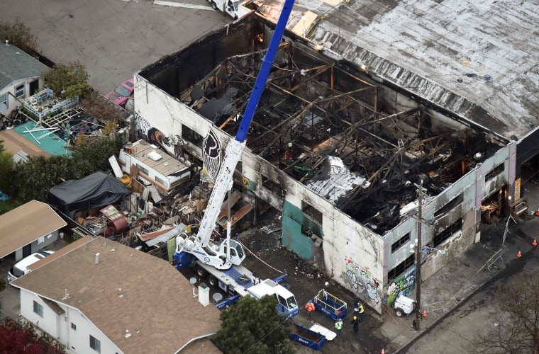 Image: A crane is used to lift wreckage in a fire-ravaged warehouse in Oakland