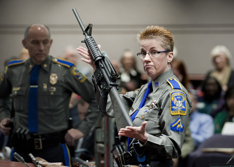 Image: A firearms training unit detective holds up a Bushmaster AR-15 rifle