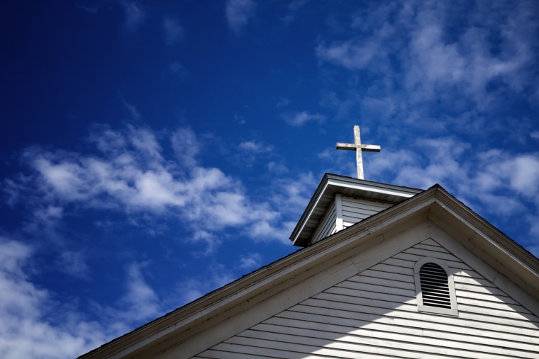 Image: Wooden cross on a simple steeple set against a sunny summer blue sky.