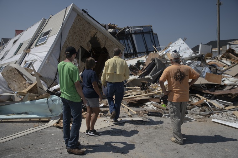 A family looks at their destroyed home Saturday with an insurance adjuster after a tornado caused by Hurricane Dorian tore through a mobile home park in Emerald Isle, North Carolina, days earlier. Residents had just recovered from Hurricane Florence, which flooded the park one year ago.