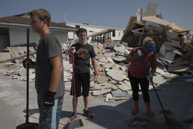 Brody Napier, Tyler Holland Napier and Adina Napier, clean up outside of Artisan and Granite Inc. a countertop company in Emerald Isle, North Carolina, on Saturday after a tornado caused massive destruction in the area. The business owned by a mother and son had contracts out for the next three months, but the owners are also concerned about their 13 employees.