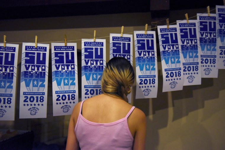 Linzy Mora, 22, hangs screen prints as election results come in during the Bexar County Democratic Party's election night party in San Antonio, Texas