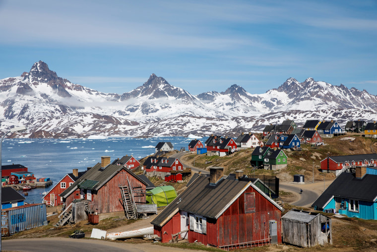 Image: Snow covered mountains rise above the harbor and town of Tasiilaq, Greenland.