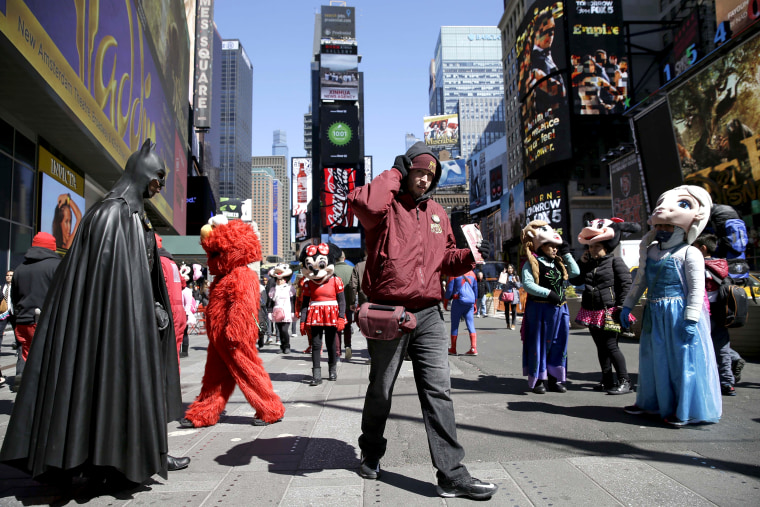 A bus tour ticket seller, center, walks through a group of costumed characters in Times Square in New York on March 29, 2016.