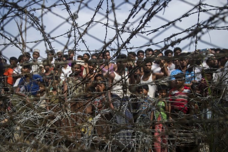 Image: Rohingya refugees gathering behind a barbed-wire fence in a temporary settlement setup in a \"no man's land\" border zone between Myanmar and Bangladesh