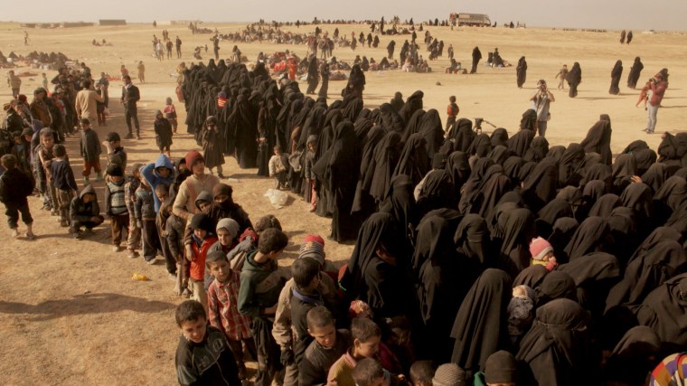 Image: Women and children, who fled Baghouz, line up for food and water in March 2019.