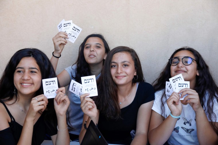 Image: Supporters of the Arab Joint List alliance hold campaign stickers in the northern Israeli Arab town of Sakhnin