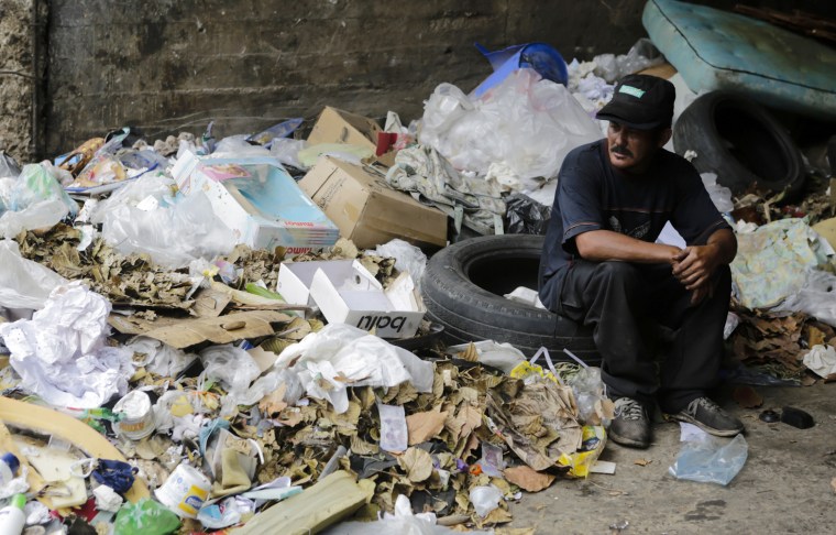 Carlos, 30, sits on a pile of trash where he looks for food in Caracas
