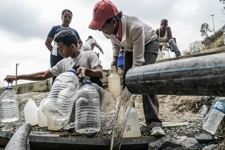 Residents collect water released through a pipe in an abandoned construction site which contains chemicals products