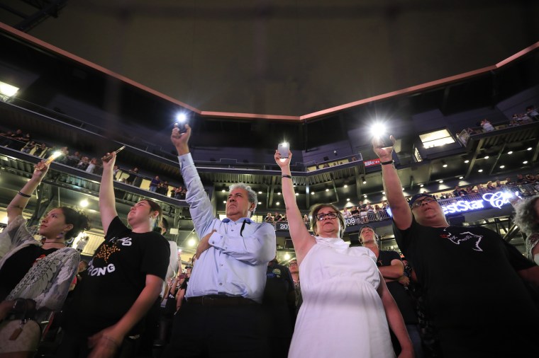 People hold up their cellphones as the names of the victims of the Aug. 3 mass shooting are read during a memorial service on in El Paso, Texas, on Aug. 14, 2019.
