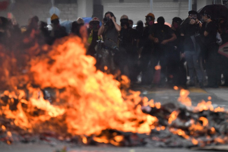 Image: Protesters look on as a barricade burns during rallies and protests through the streets of Hong Kong