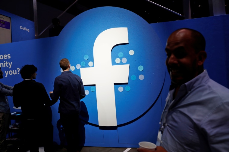 Attendees walk past a Facebook logo during Facebook Inc's F8 developers conference in San Jose