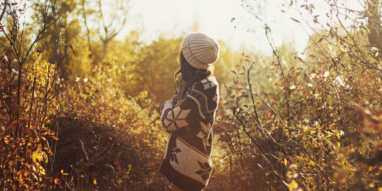 Woman in sweater walking in autumn forest