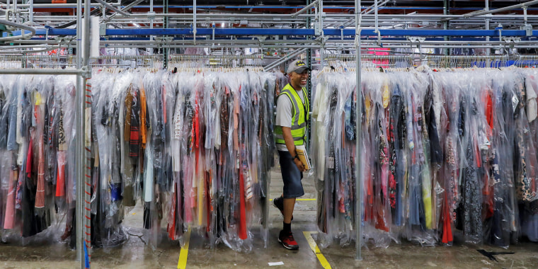 A person moves through clothing in the storage area at Rent the Runway's "Dream Fulfillment Center" in Secaucus, New Jersey