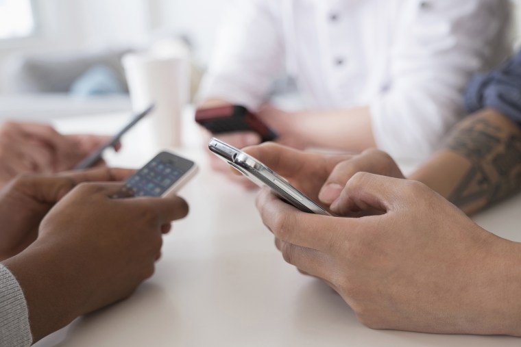 Close up of friends texting with cell phones at table