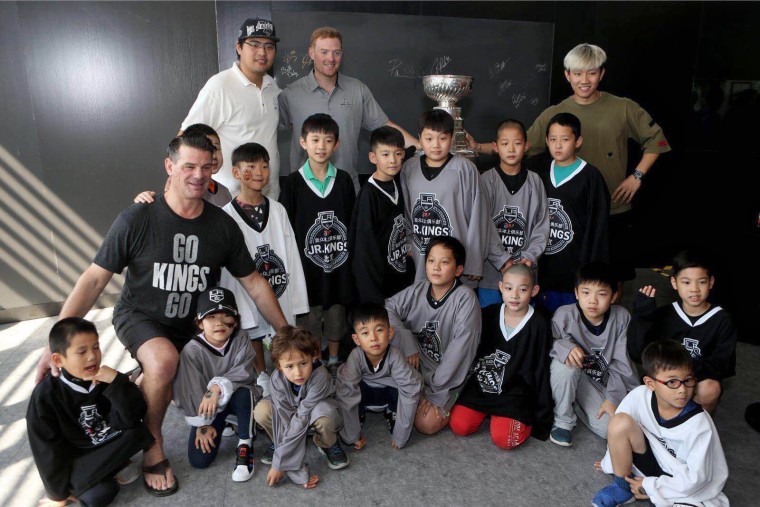 Todd Elik, head coach of the Beijing Jr. Kings, left, and goalie coach Mitch O'Keefe, wearing grey shirt, pose with members of the Beijing Jr. Kings.