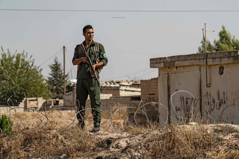 Image: A member of the Kurdish Internal Security Forces of Asayesh stands guard during a demonstration by Syrian Kurds against Turkish threats in the town of Ras al-Ain in Syria's Hasakeh province near the Turkish border